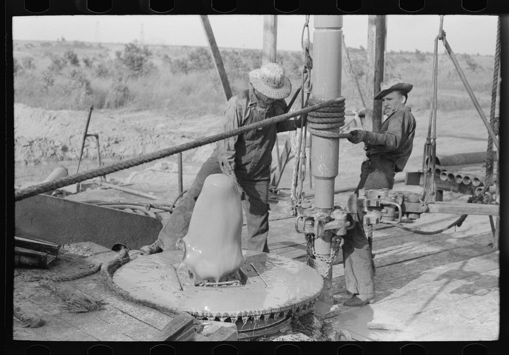 Adding a length of drilling pipe at oil well in Seminole oil field, Oklahoma. Lower end of traveling block is attached to…