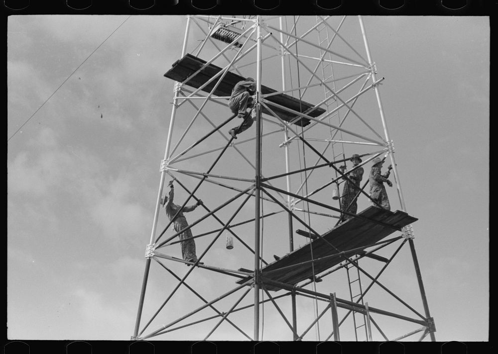 Roustabouts painting an oil well, Seminole oil fields, Oklahoma. by Russell Lee