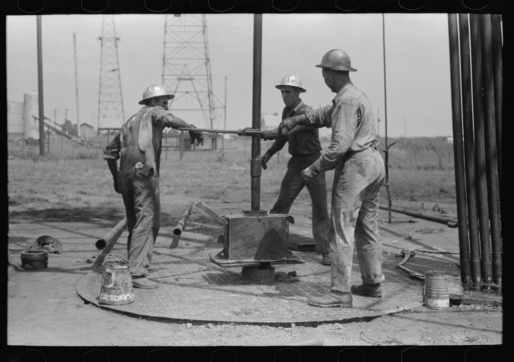 [Untitled photo, possibly related to: Roughnecks leaning on the wrench to tighten the joint in the pipe, oil well, Oklahoma…