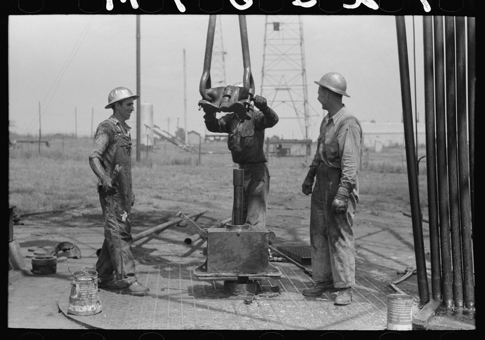 [Untitled photo, possibly related to: Roughnecks leaning on the wrench to tighten the joint in the pipe, oil well, Oklahoma…