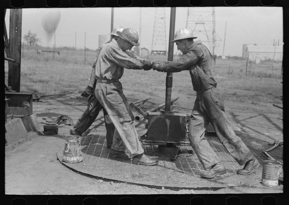Roughnecks leaning on the wrench to tighten the joint in the pipe, oil well, Oklahoma City, Oklahoma by Russell Lee