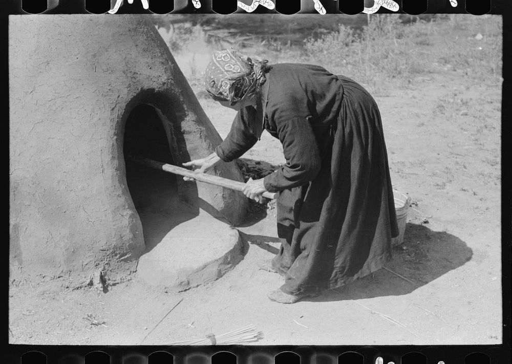 [Untitled photo, possibly related to: Spanish-American woman putting loaf of bread into oven, Taos County, New Mexico] by…