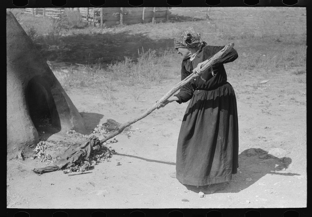 Pulling out hot coals with wet cloth, Taos County, New Mexico by Russell Lee