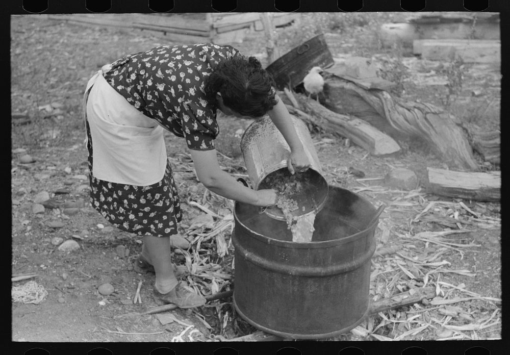 Spanish-American FSA (Farm Security Administration) client emptying pail of grease into kettle for purpose of making soap…