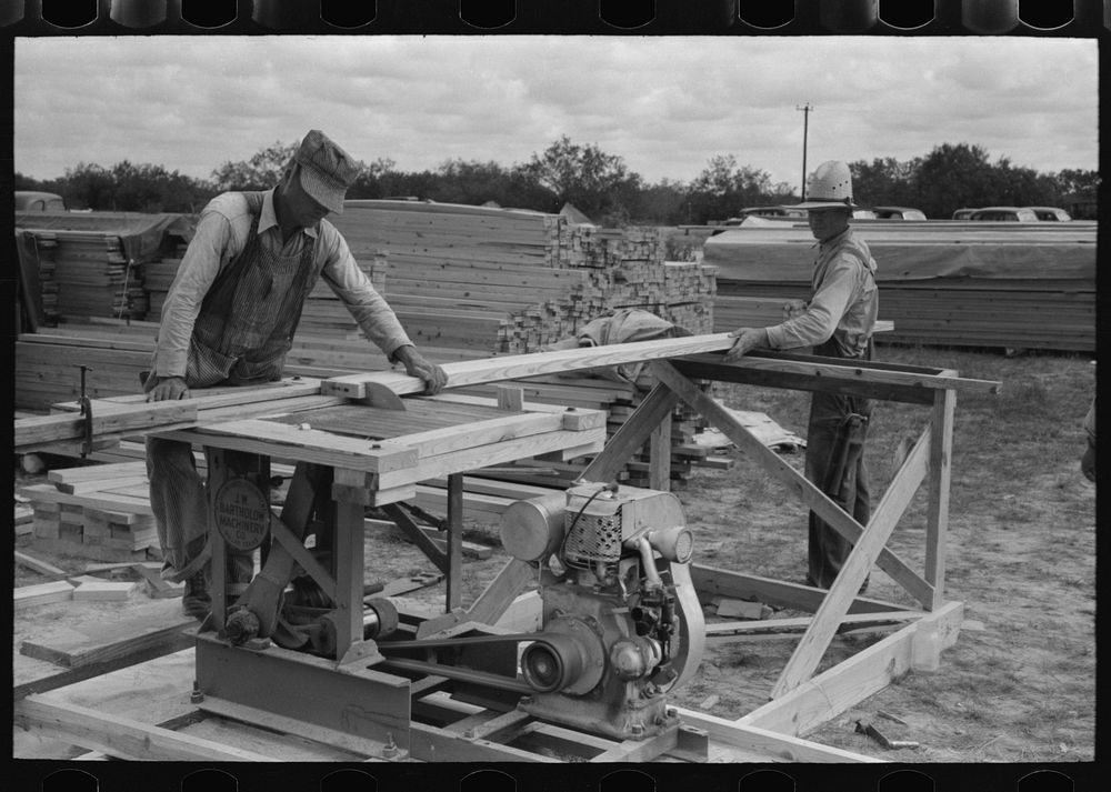 [Untitled photo, possibly related to: Cutting two-by-fours into identical lengths at migrant camp under construction at…