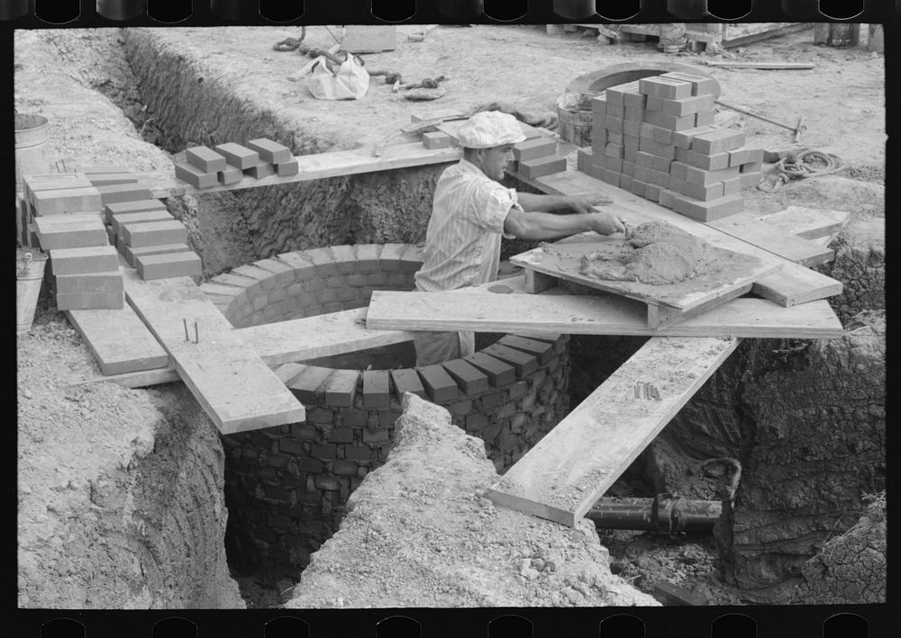 [Untitled photo, possibly related to: Laying bricks in construction of manhole at migrant camp at Sinton, Texas] by Russell…