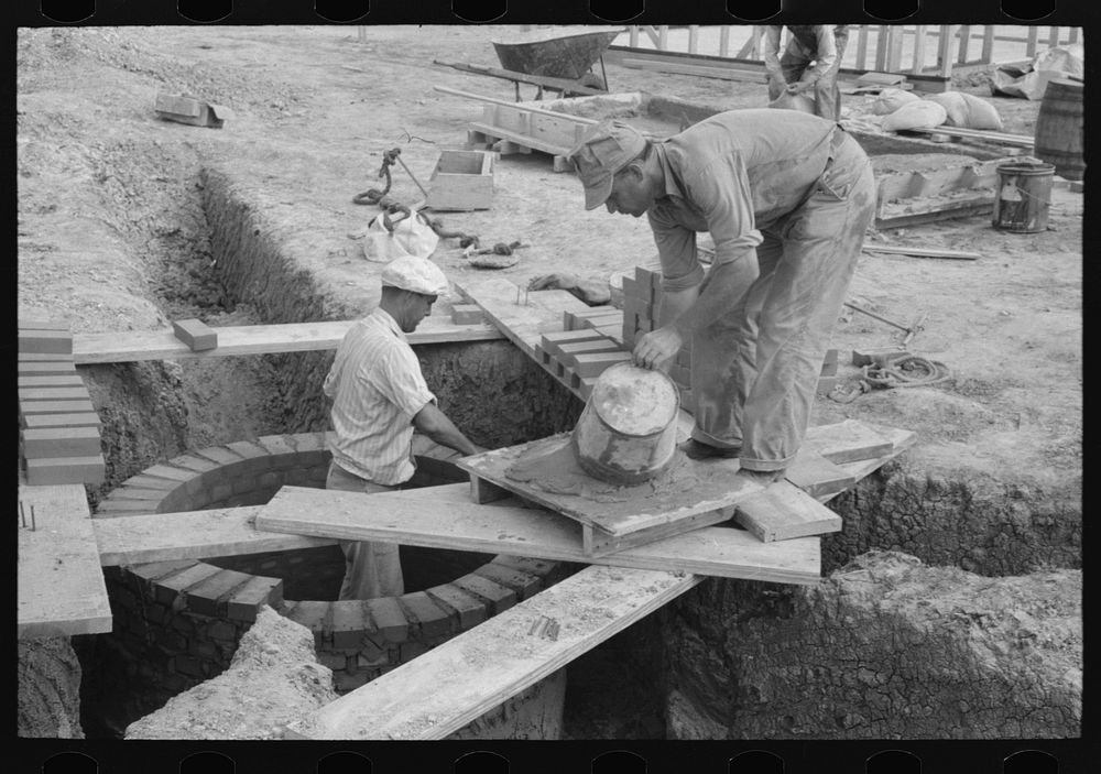 Laying bricks in construction of manhole at migrant camp, Sinton, Texas by Russell Lee
