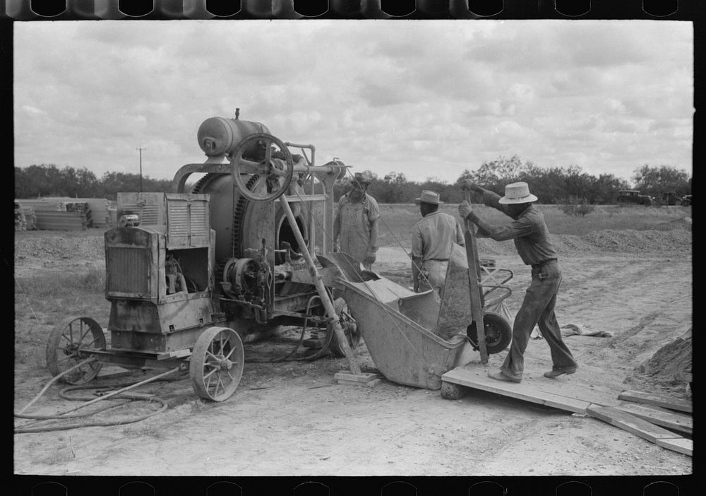 Dumping materials into concrete mixer at migrant camp under construction at Sinton, Texas by Russell Lee