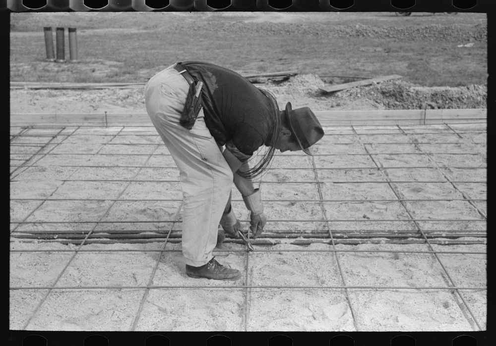 Tying iron reinforcement bars together before pouring concrete at migrant camp under construction at Sinton, Texas by…