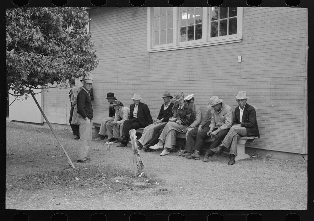 Men sitting on a bench at county fair, Gonzales, Texas by Russell Lee