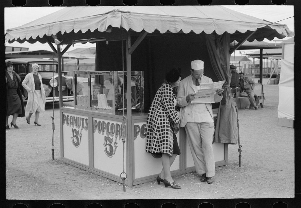 Popcorn man and his wife studying the map, county fair, Gonzales, Texas by Russell Lee