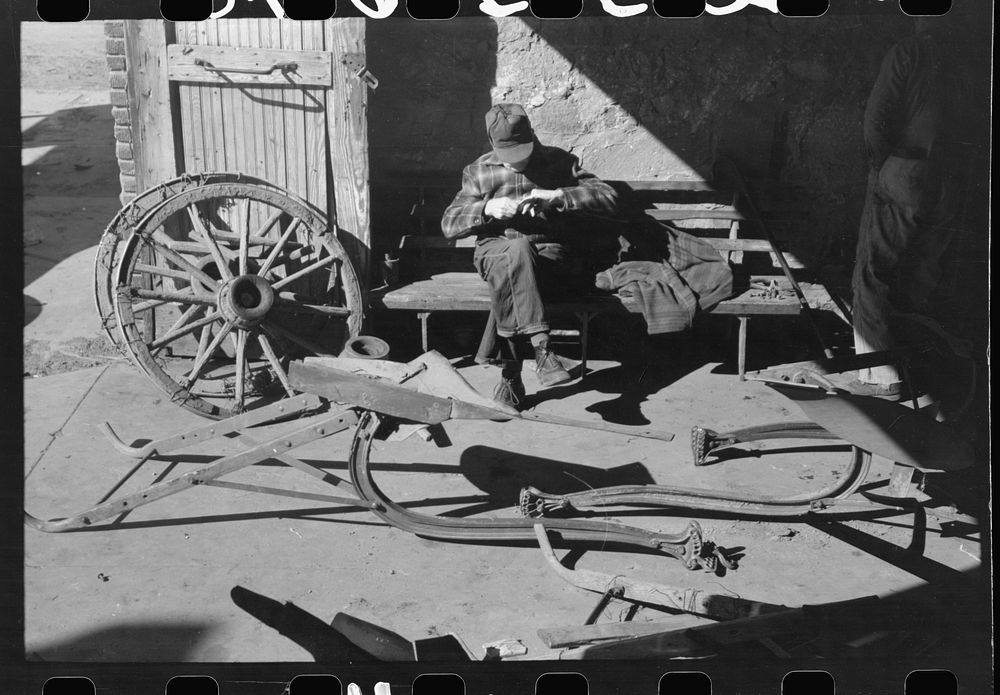 [Untitled photo, possibly related to: Blacksmith's helper disassembling plow belonging to Pomp Hall,  tenant farmer from…
