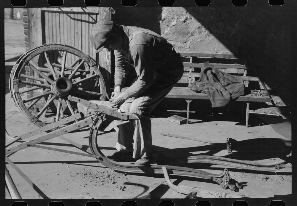 [Untitled photo, possibly related to: Blacksmith's helper disassembling plow belonging to Pomp Hall,  tenant farmer from…