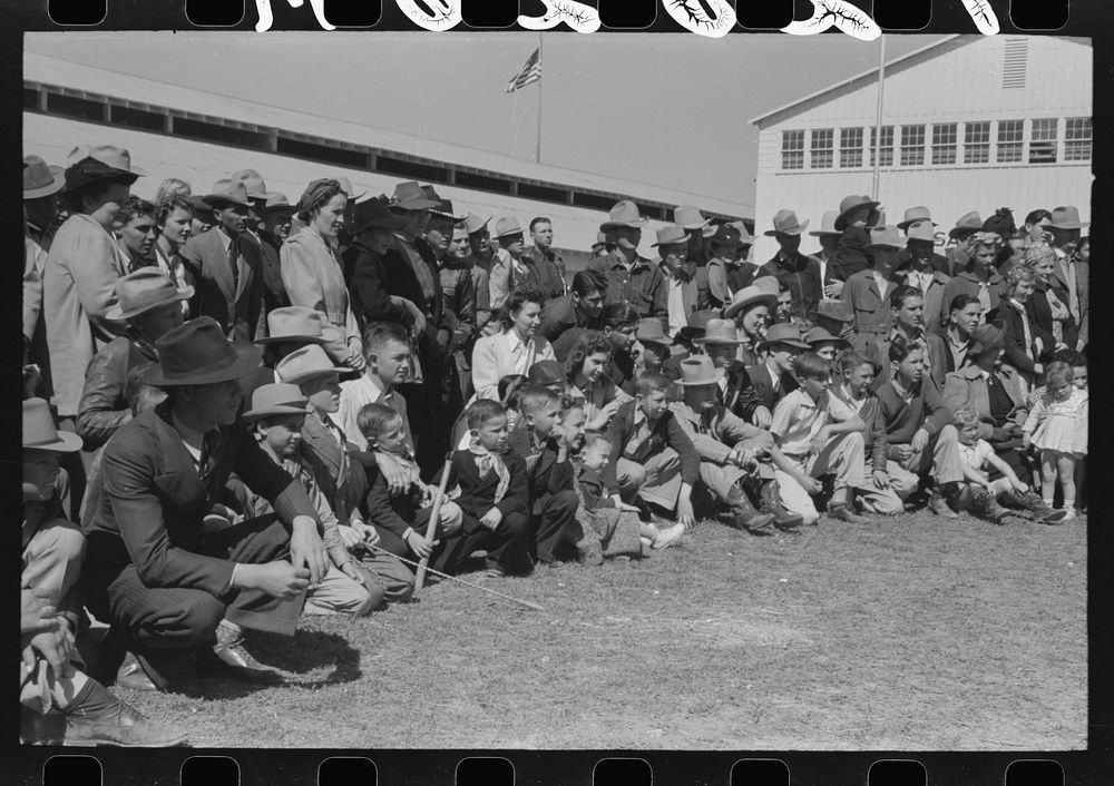 Group of spectators at sideshow watching man unloosen himself from chains.  San Angelo Fat Stock Show, San Angelo, Texas by…