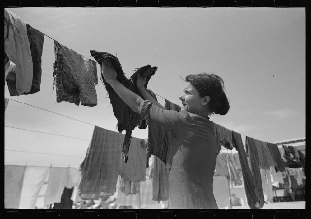 [Untitled photo, possibly related to: Wife of migratory worker hanging up laundry at the Agua Fria Migratory Labor Camp…