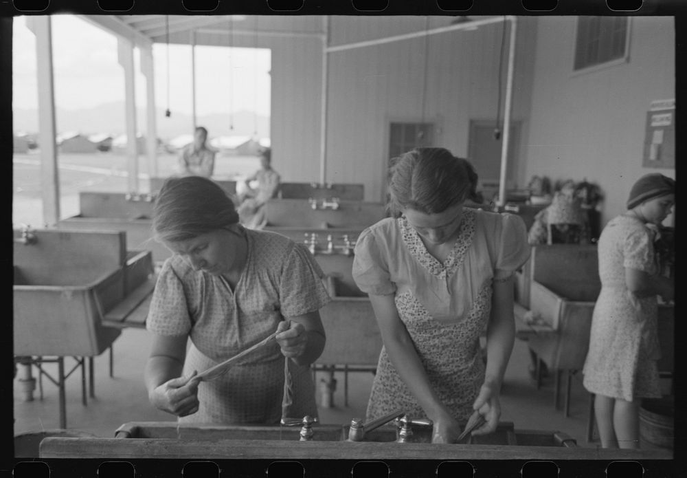 Wives of migratory laborers washing their family laundry at the Agua Fria Migratory Labor Camp, Arizona. The difference in…