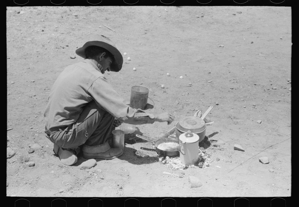 Faro Caudill frying eggs over camp fire the day he was moving his dugout. Pie Town, New Mexico by Russell Lee
