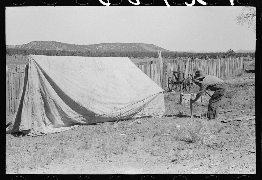 Faro Caudill driving tent posts; the family will live in the tent while the dugout is being rebuilt. Pie Town, New Mexico by…