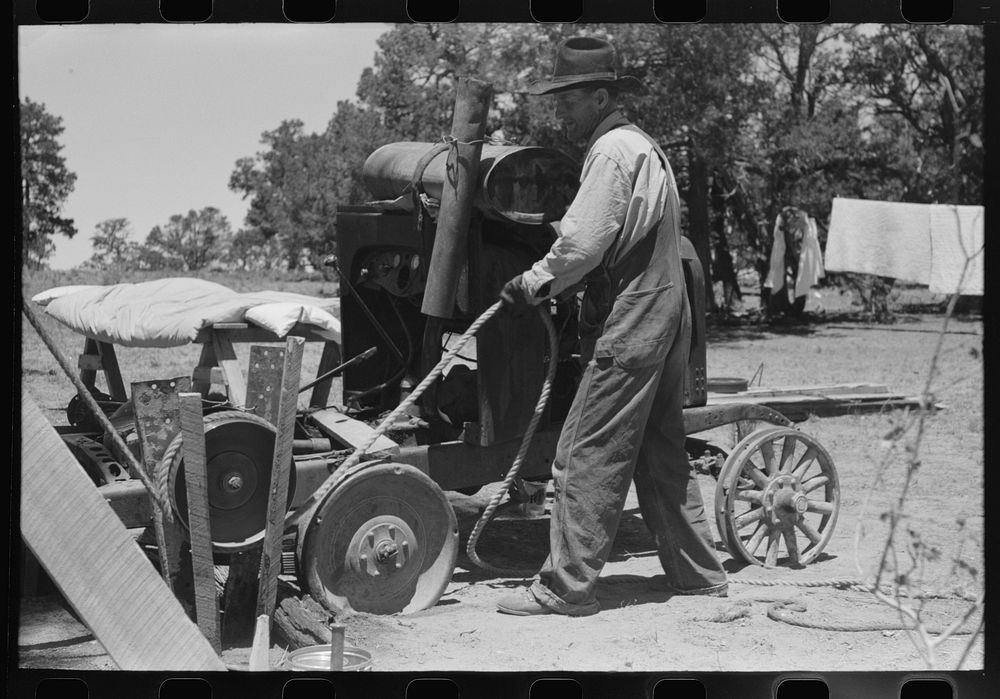 Farmer drilling water well. In this picture he is loosening and tightening rope around the pulley, thus raising and lowering…