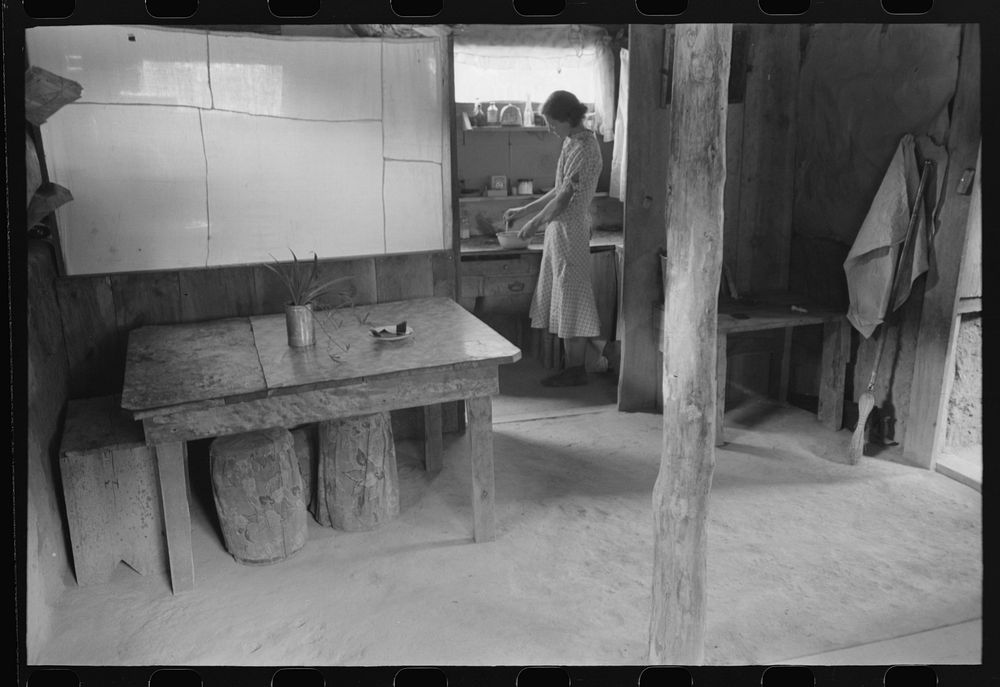 Mrs. Whinery working in her kitchen. This picture shows the dirt floor of the dugout and the natural lighting. Pie Town, New…