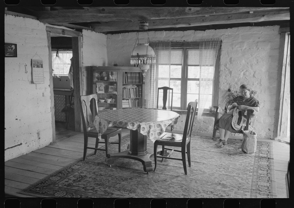Wife of homesteader working in dining room of her new adobe house. The lamp-chandelier above dining table was brought by her…