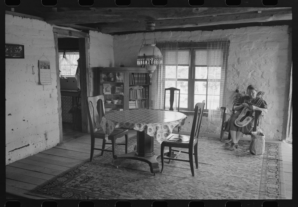 [Untitled photo, possibly related to: Wife of homesteader working in dining room of her new adobe house. The lamp-chandelier…