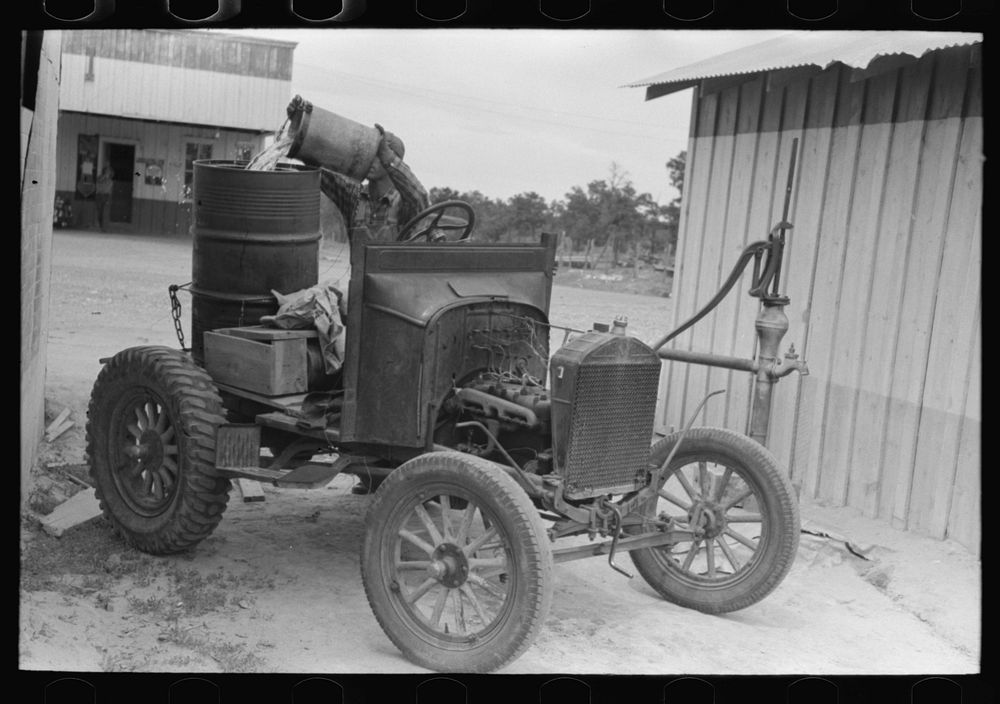 [Untitled photo, possibly related to: Homesteader pumping water which he will haul home from town. Wells require cash to…
