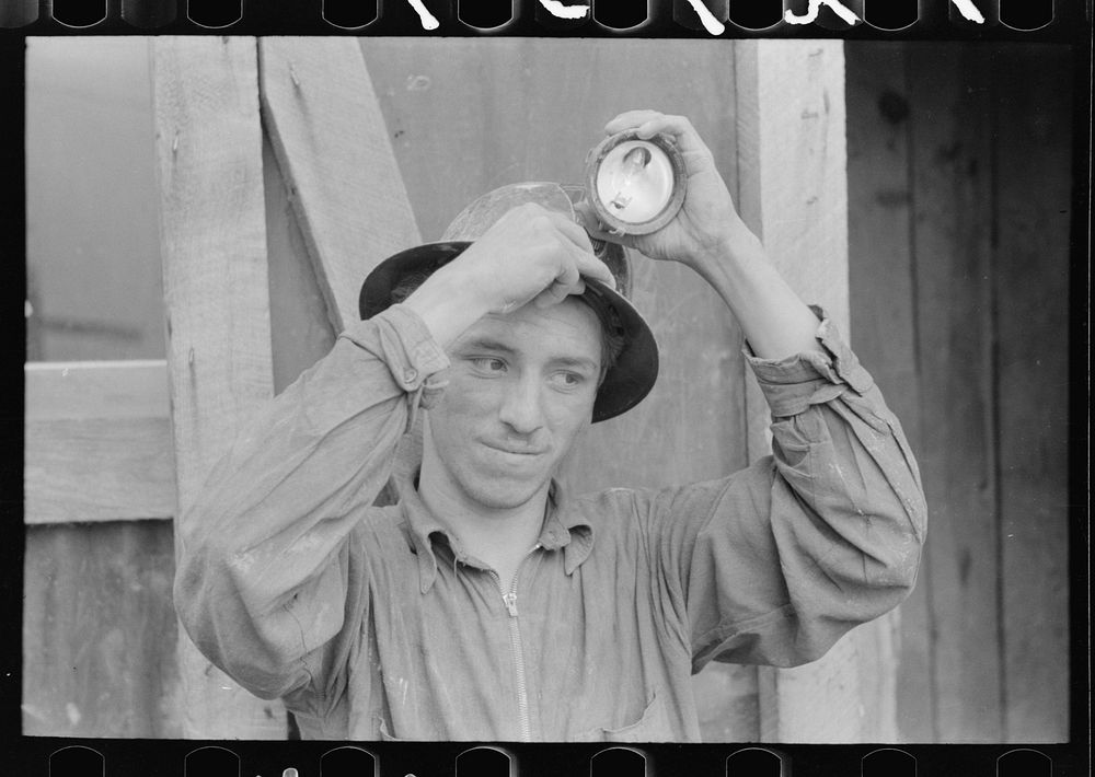 Young mine worker taking lamp from his hat at the end of the day's work, Mogollon, New Mexico by Russell Lee