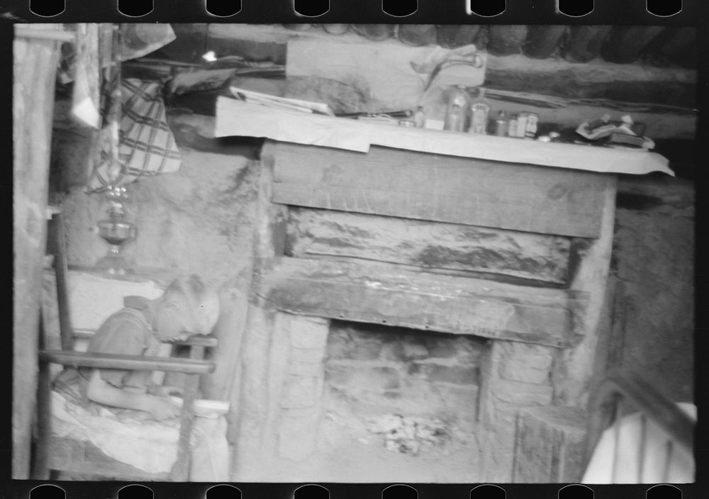 [Untitled photo, possibly related to: Mr. Leatherman's son reading in front of fireplace in dugout, Pie Town, New Mexico] by…