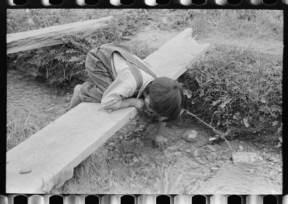 Spanish-American boy playing in irrigation ditch, Chamisal, New Mexico by Russell Lee