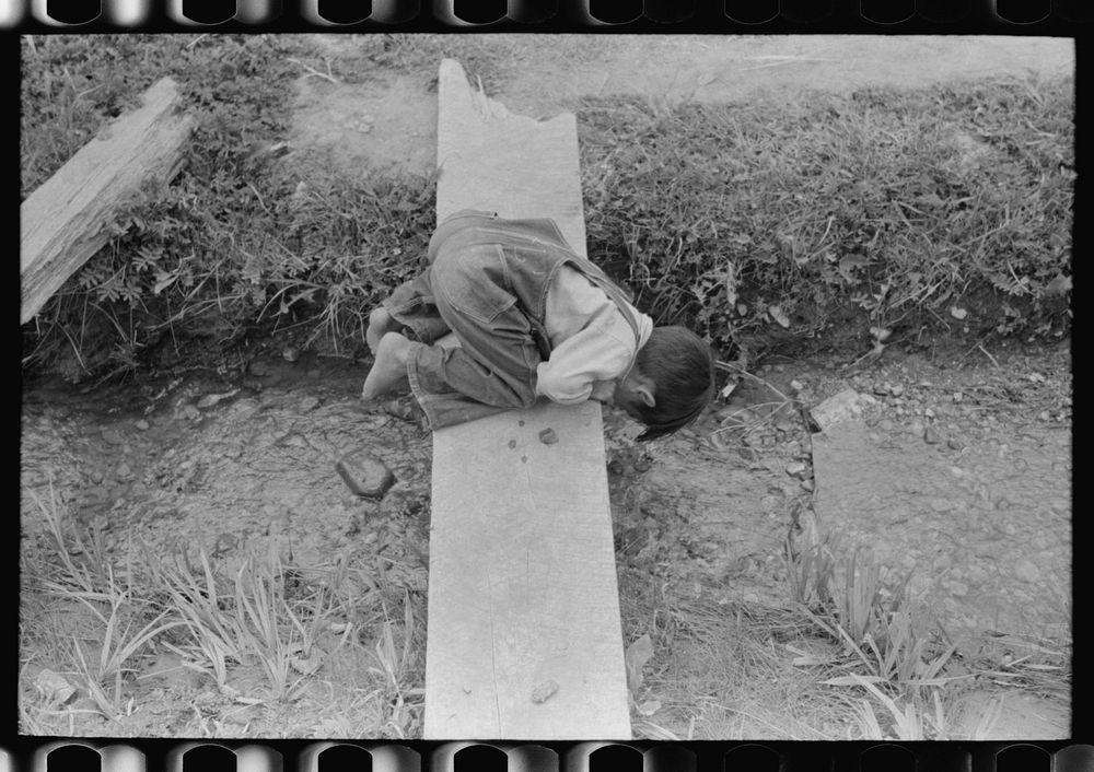 [Untitled photo, possibly related to: Spanish-American boy playing in irrigation ditch, Chamisal, New Mexico] by Russell Lee
