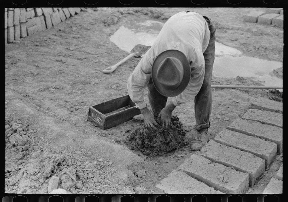 Mixing adobe for making bricks, Chamisal, New Mexico by Russell Lee