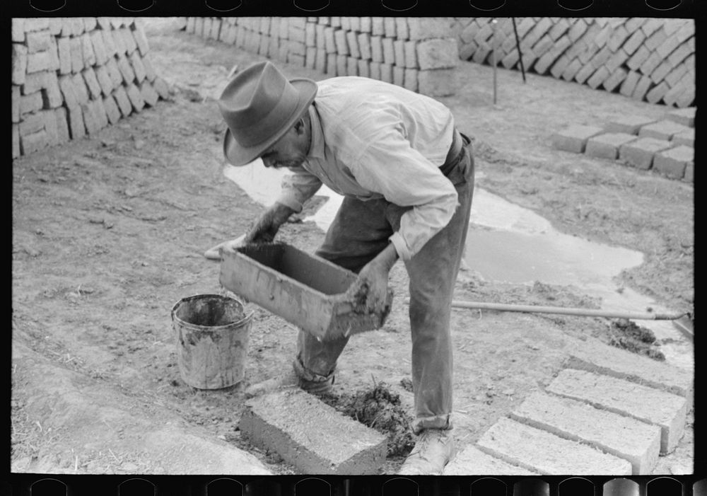 Spanish-American removing form shaped adobe brick. The adobe brick is next dried by the sun. Chamisal, New Mexico by Russell…