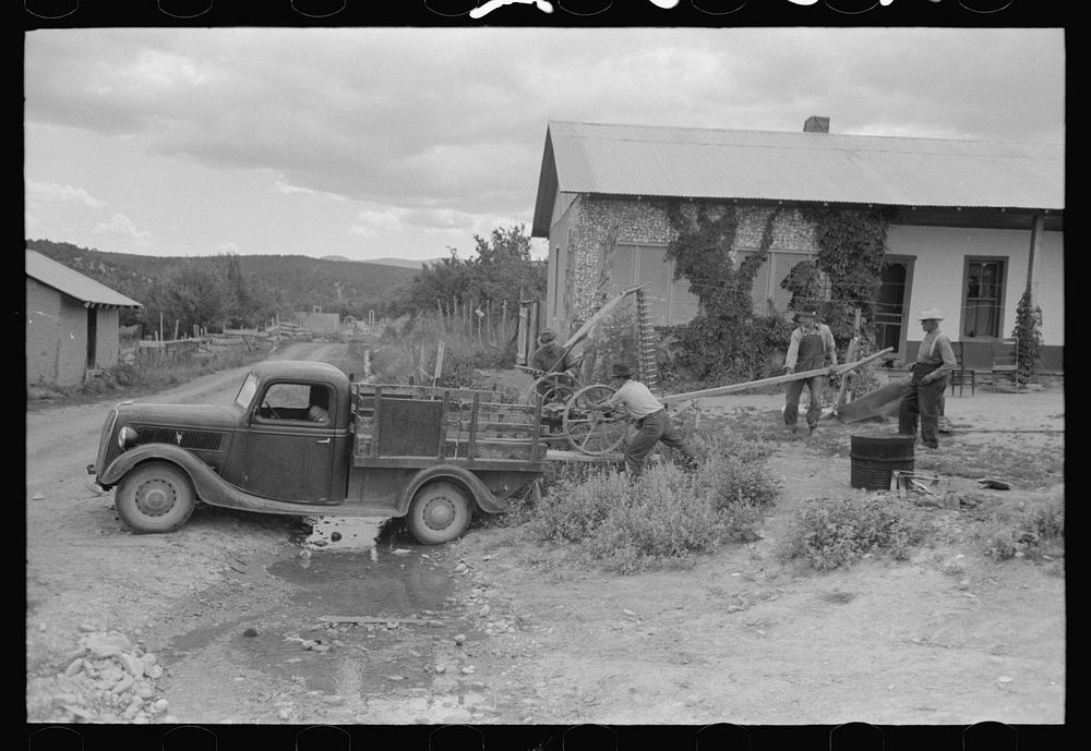 Spanish-American farmers loading a mower onto a track, Chamisal, New Mexico by Russell Lee