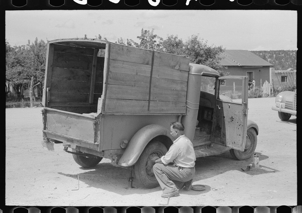 Merchant changing tire on his truck, Penasco, New Mexico by Russell Lee
