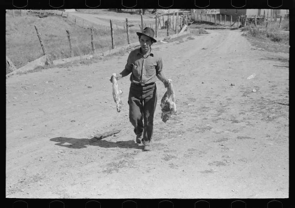 Spanish-American farmer with fresh pork from hog he has just slaughtered and dressed. Chamisal, New Mexico by Russell Lee