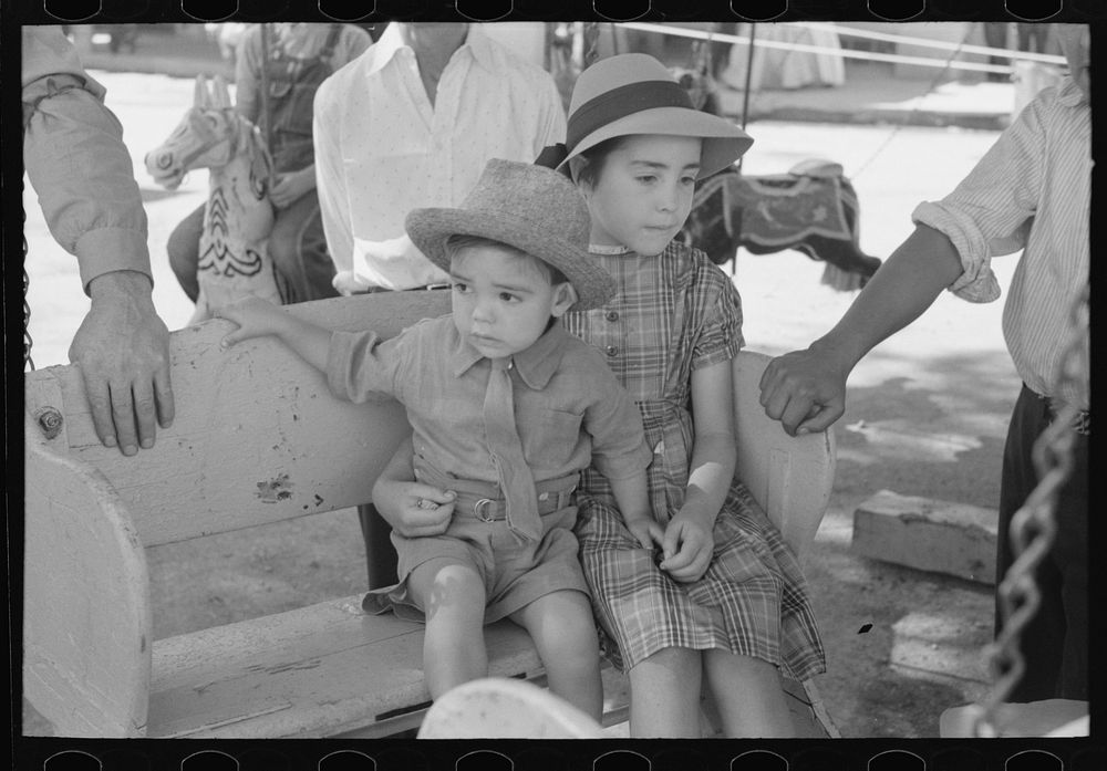 Spanish-American children waiting for a ride on the merry-go-round, Fiesta, Taos, New Mexico by Russell Lee