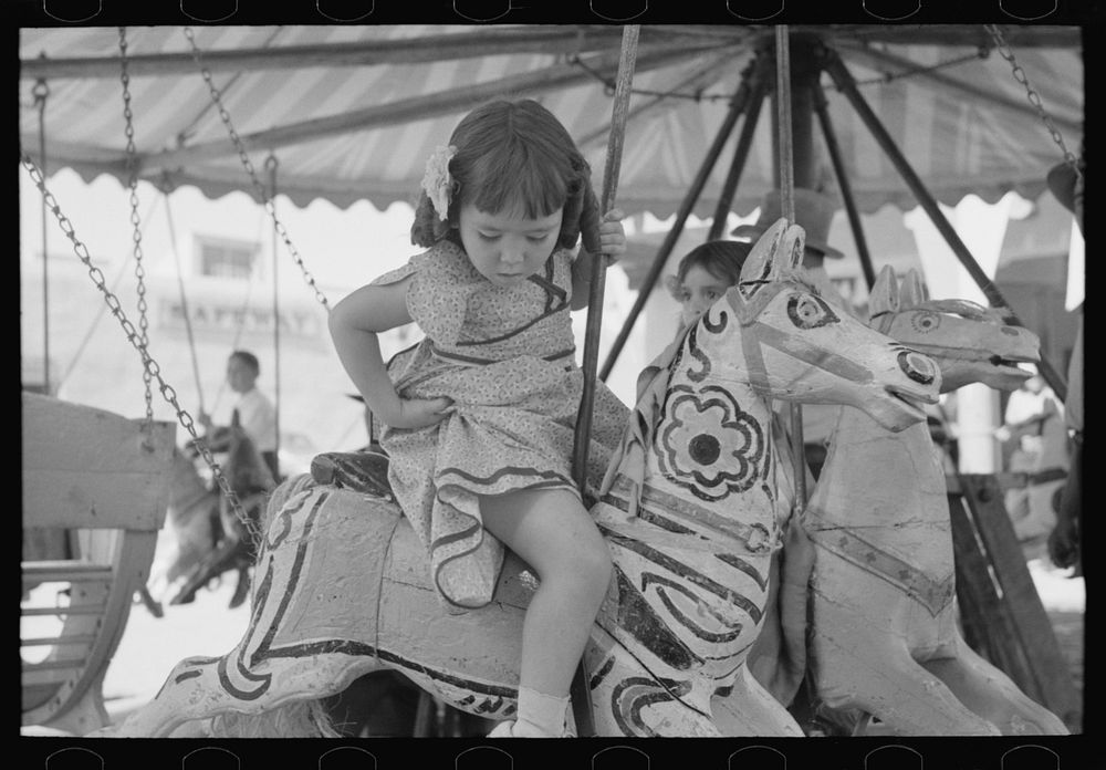 Little girl on the merry-go-round horse. Fiesta, Taos, New Mexico by Russell Lee