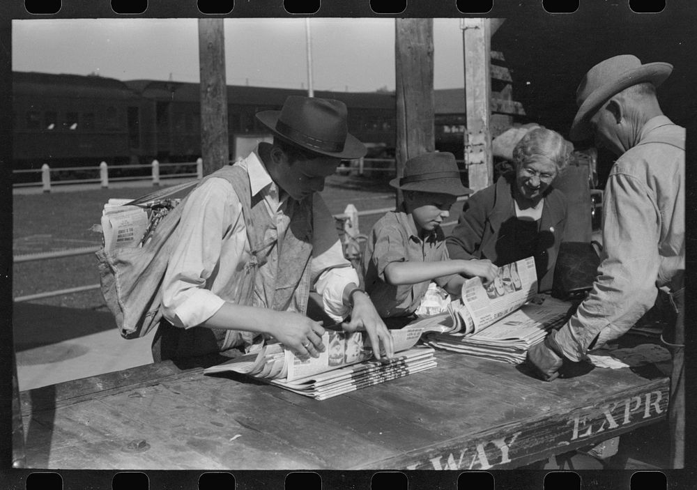 Newsboys getting the papers just after the arrival of the morning train, Montrose, Colorado. While there is a daily paper in…