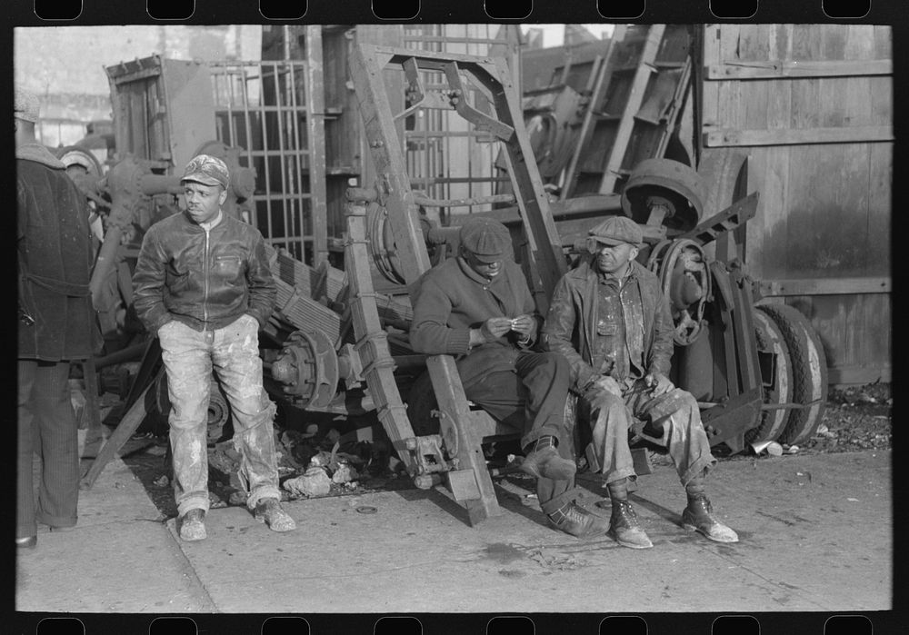 Men sitting on parts of truck in junkyard, South Side of Chicago, Illinois by Russell Lee