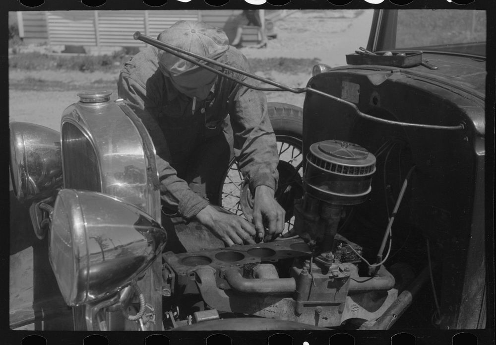 Farm worker at work on his automobile. FSA (Farm Security Administration) labor camp. Caldwell, Idaho by Russell Lee