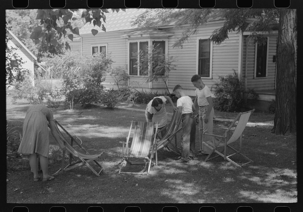 Caldwell, Idaho. Putting the deck chairs out on the shady lawn by Russell Lee