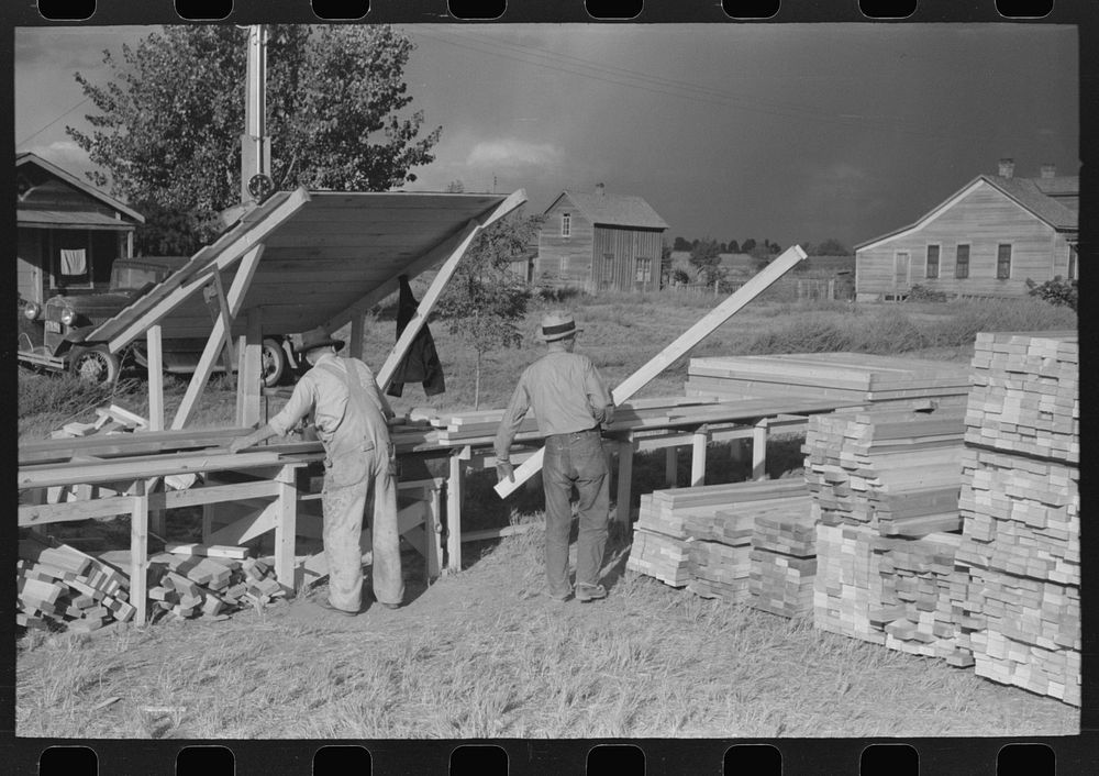 [Untitled photo, possibly related to: Cutting lumber to length for construction for sanitary units at FSA (Farm Security…