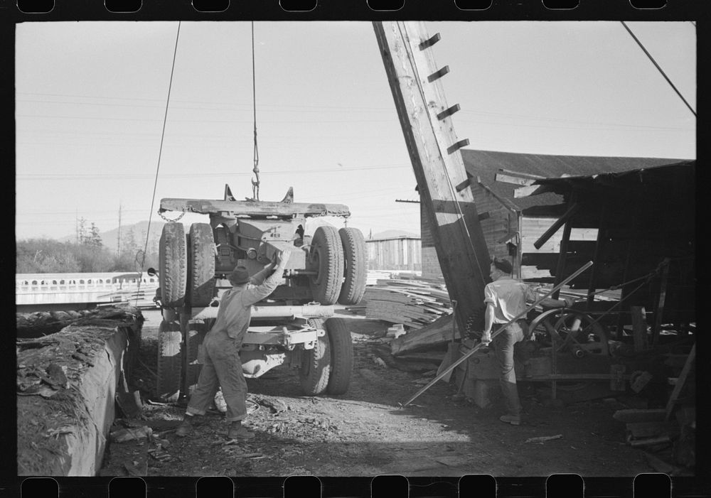 Loading onto trailer truck, logging operations, Tillamook County, Oregon. The trailer is carried on the truck when it…