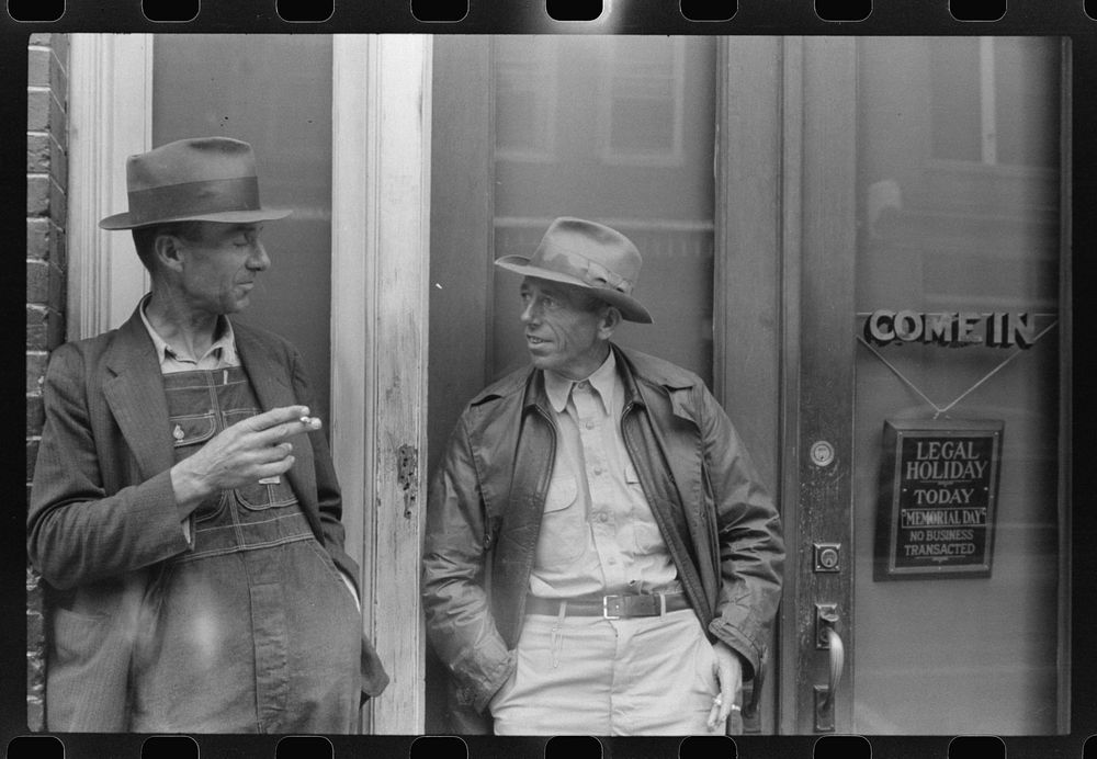 Two farmers talking in front of a bank in Roxboro, North Carolina. Sourced from the Library of Congress.