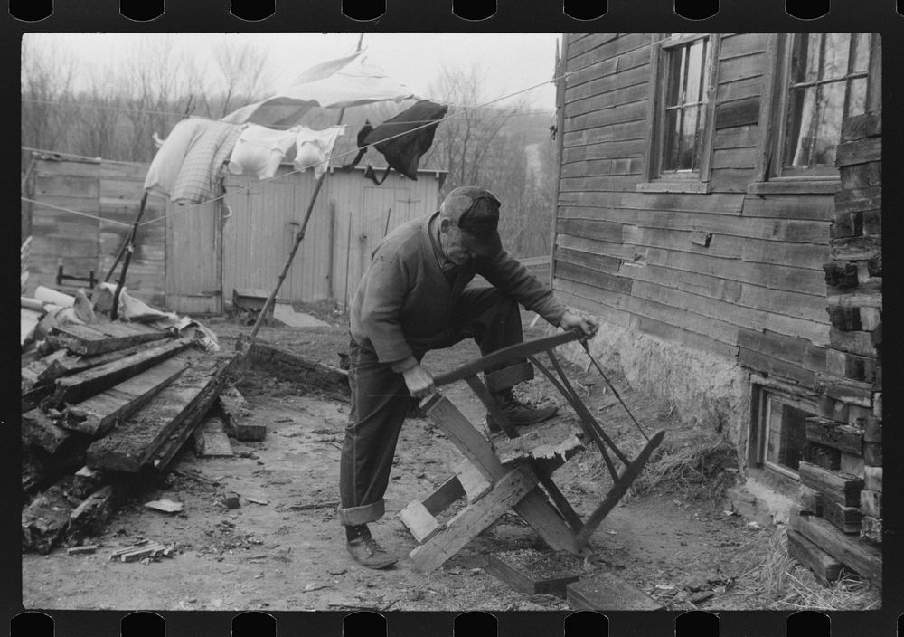 Old man, French Canadian, who worked in a paper mill for eleven years, in front of his house sawing wood, Montville…