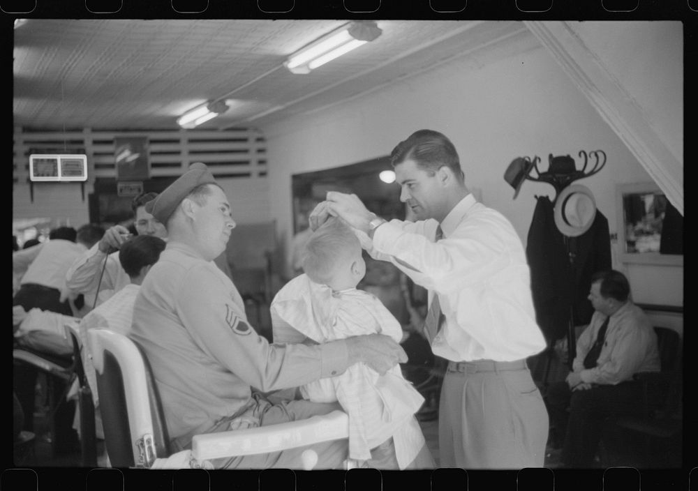 Sergeant from Fort Benning getting his son's hair cut at a barber shop in Columbus, Georgia. Sourced from the Library of…