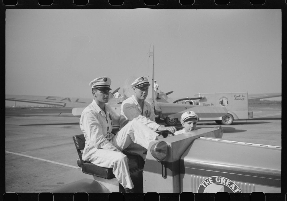 Washington, D.C. Workers at the municipal airport riding a little truck used to haul baggage and freight around the field.…