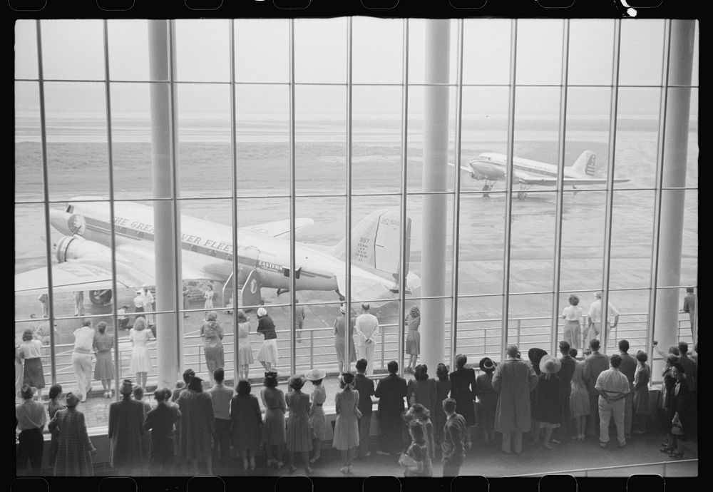 Visitors watching planes through the window of the main waiting room at the municipal airport in Washington, D.C.. Sourced…