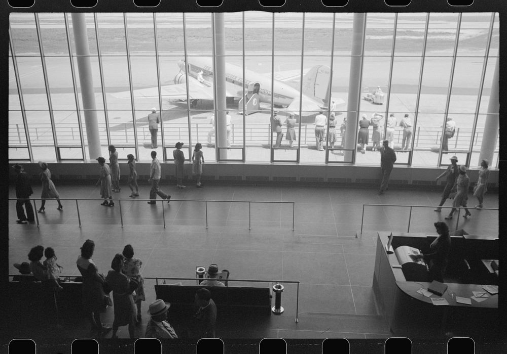 [Untitled photo, possibly related to: Visitors watching planes through the window of the main waiting room at the municipal…